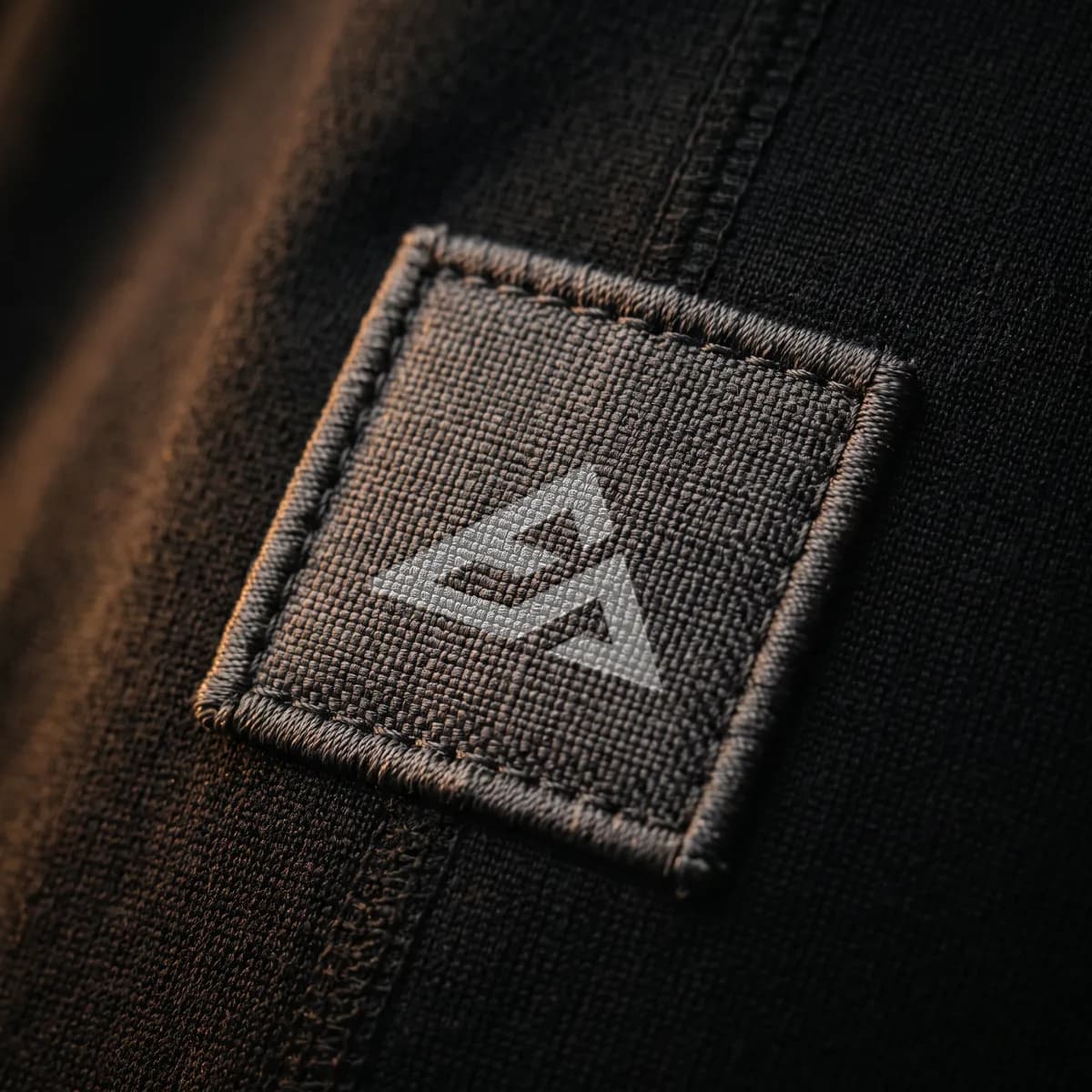 Close-up of the EA mountain mark on black performance fabric