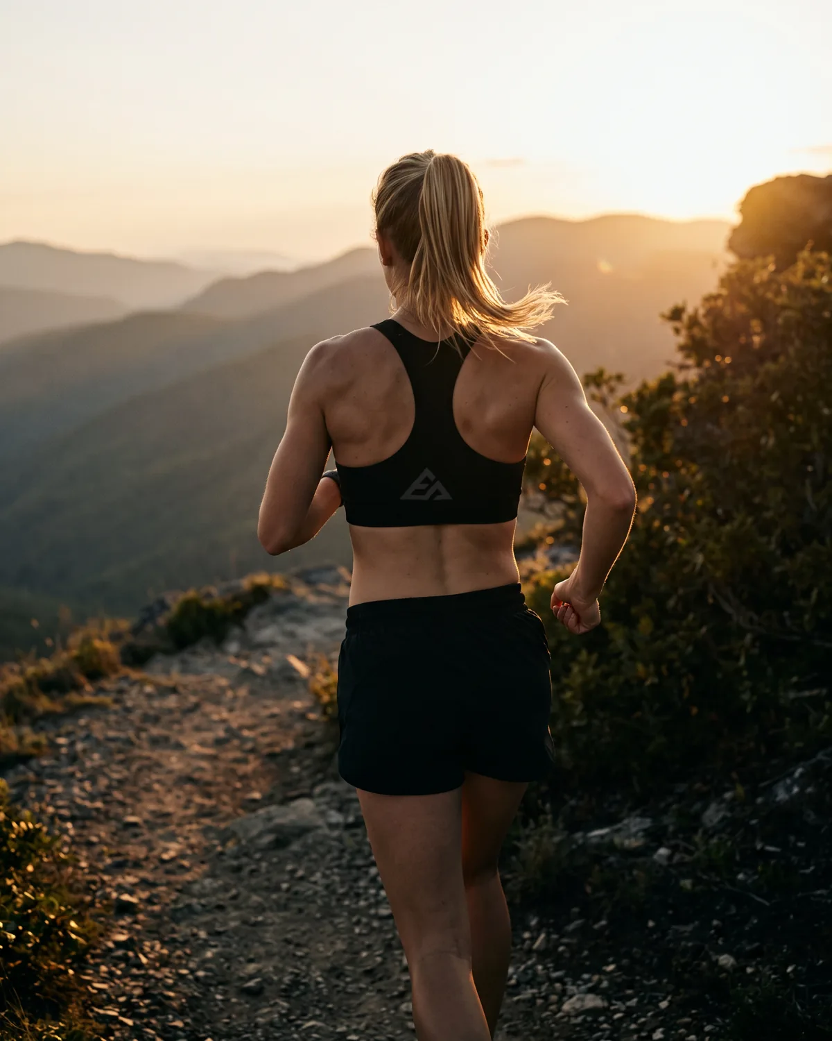 Woman running at golden hour in a black sports bra and shorts